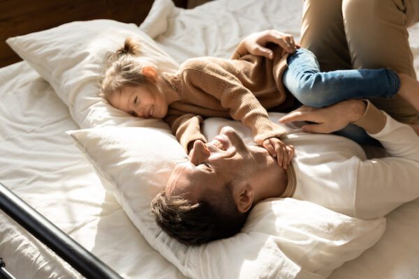 Happy,Father,And,Little,Daughter,Relaxing,In,Cozy,Bed,Together,